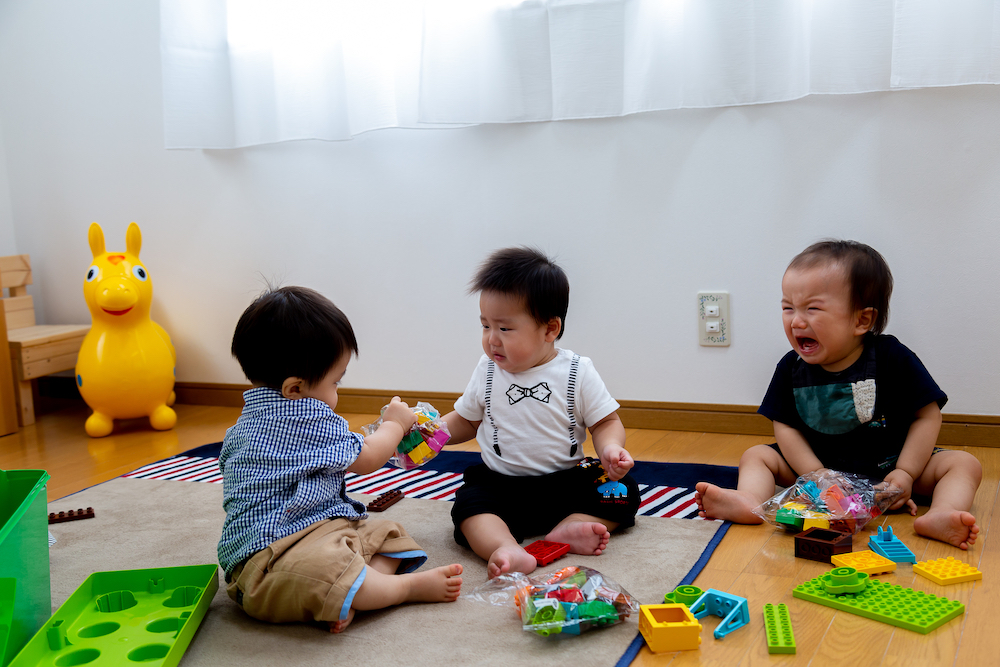 幼児3人がおもちゃを取り合う様子