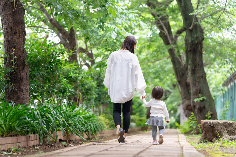 緑豊かな道で手を繋いで歩く親子