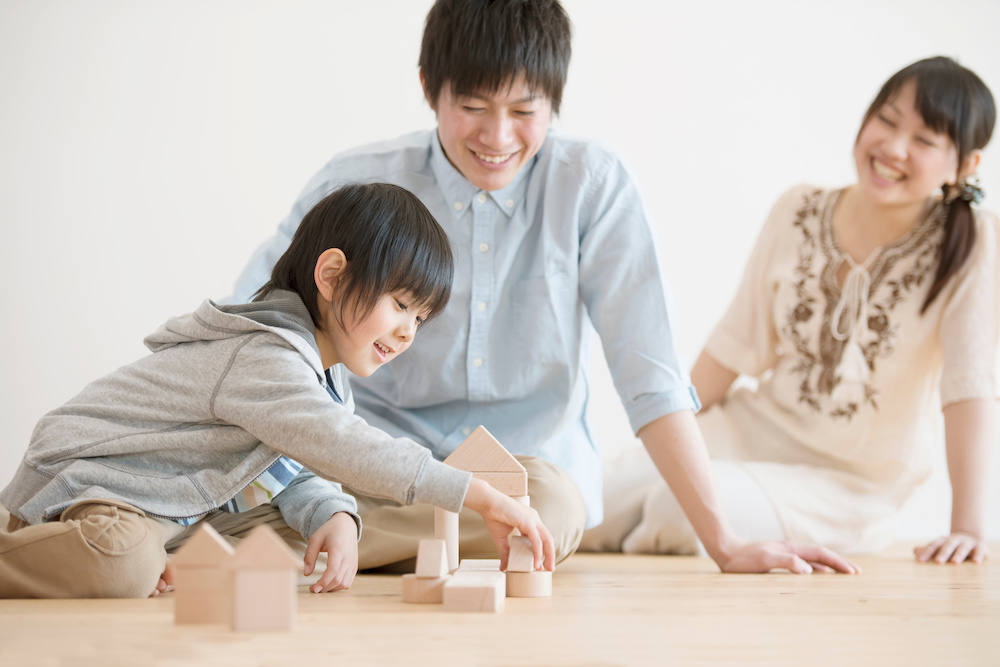 小さい子どもと両親が室内で遊んでいる様子